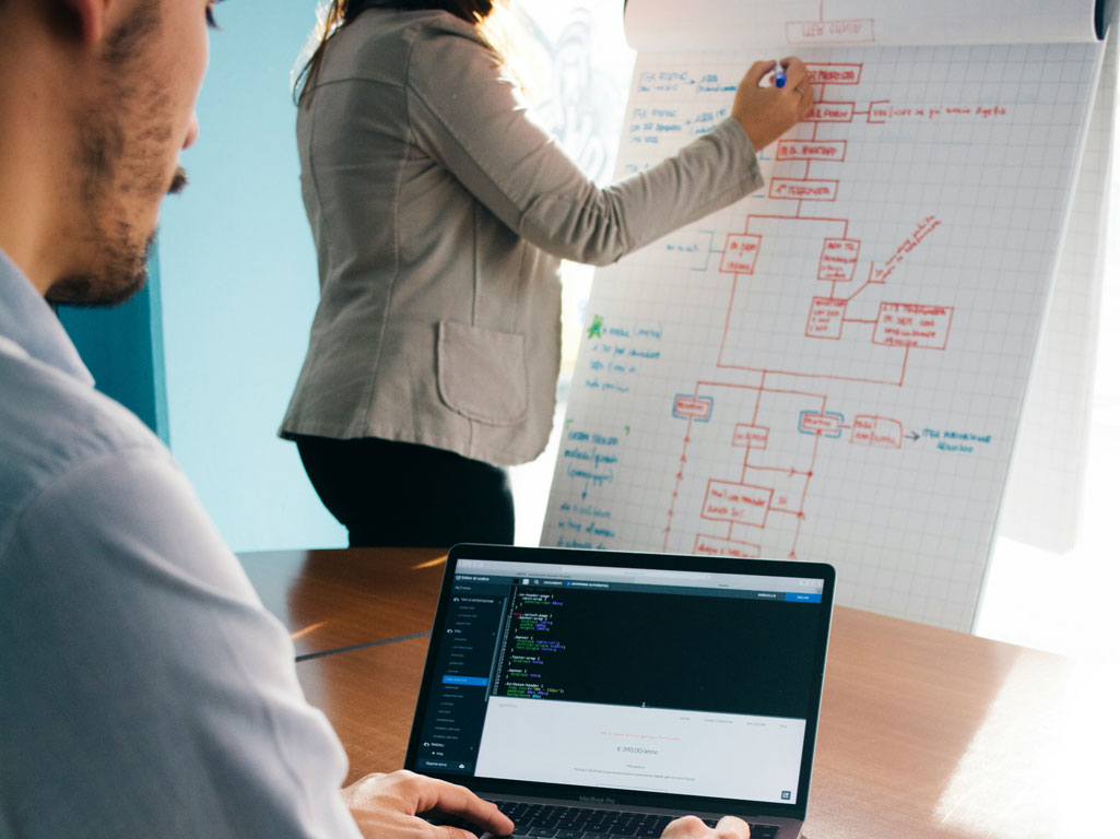 Man at computer and women writing on poster board